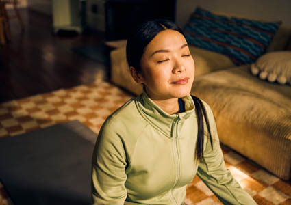 Asian American woman meditating on a bed